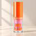 Pink glitter Miss Lara gloss bottle with orange cap on ivory vanity