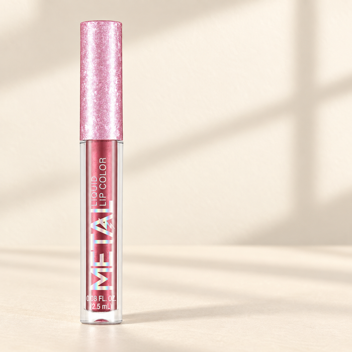 Metallic pink lip colour bottle with a textured pink cap on an ivory surface.