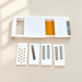 White vegetable slicer with four interchangeable inserts on an ivory surface.