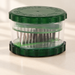Transparent garlic cutter with dark green lid and base on an ivory surface.