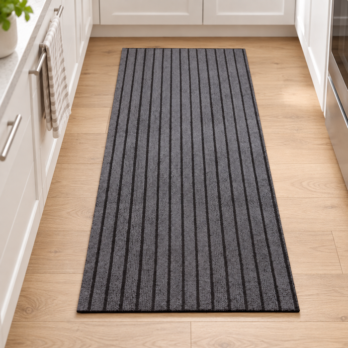 Grey striped rectangular kitchen mat on a light wooden floor.