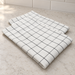 White kitchen tea towel with a fine dark checked pattern, folded on a pale countertop.