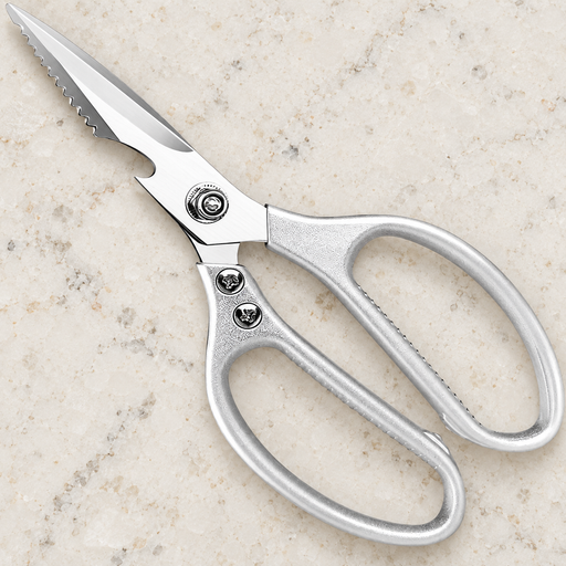 Silver kitchen scissors lying on an ivory stone worktop.
