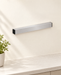 Silver knife holder with black end caps on an ivory kitchen wall.