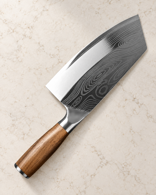 Broad kitchen knife with a patterned blade and brown handle on an ivory countertop.