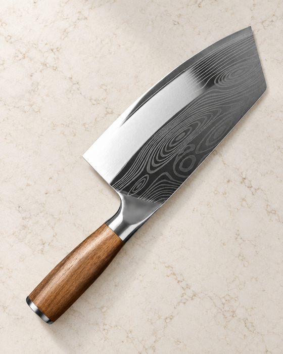 Broad kitchen knife with a patterned blade and brown handle on an ivory countertop.