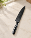 Black-handled patterned kitchen knife on a pale stone kitchen counter.