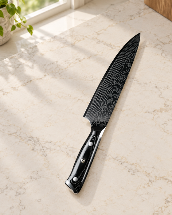 Black-handled patterned kitchen knife on a pale stone kitchen counter.