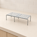 Grey expandable slotted shelf on an ivory kitchen counter