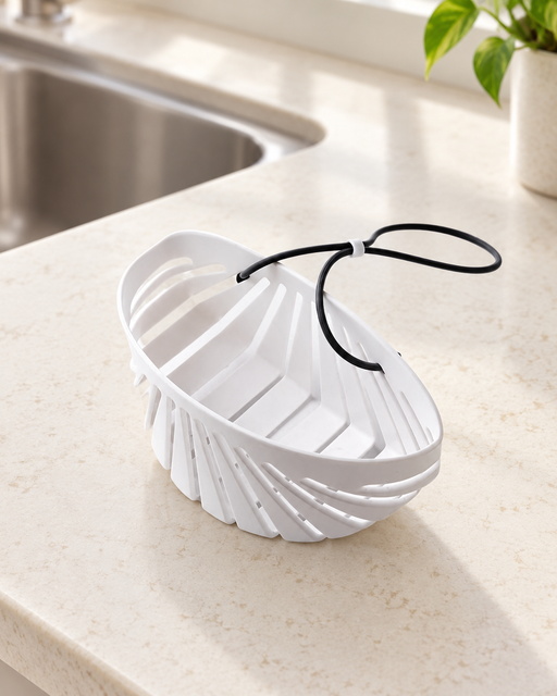White shell-shaped sink basket with black lanyard beside a kitchen sink.