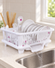 White dish draining rack holding dishes beside a kitchen sink.