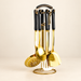 Gold-coloured kitchen utensils with black handles on a matching stand against an ivory background