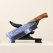 Kitchen knife with a wooden handle and patterned blade resting on a dark display stand