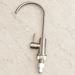 Stainless steel faucet with its mounting connector resting on an ivory worktop.