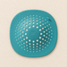 Turquoise drain cover with radial holes on ivory surface