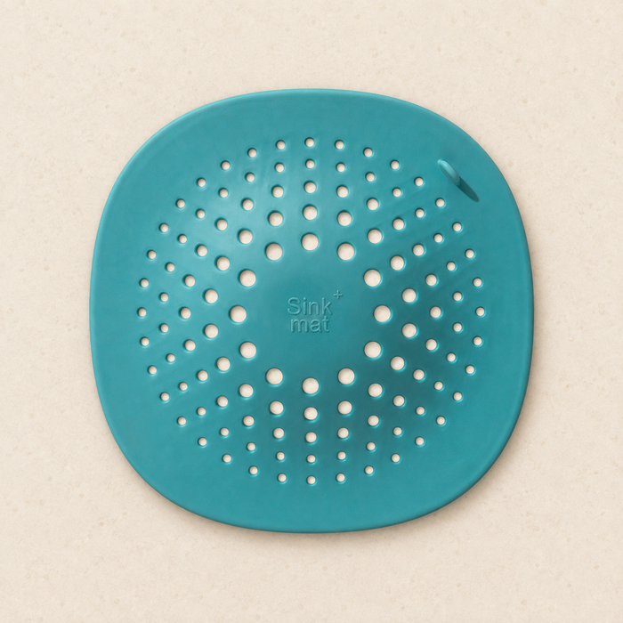 Turquoise drain cover with radial holes on ivory surface