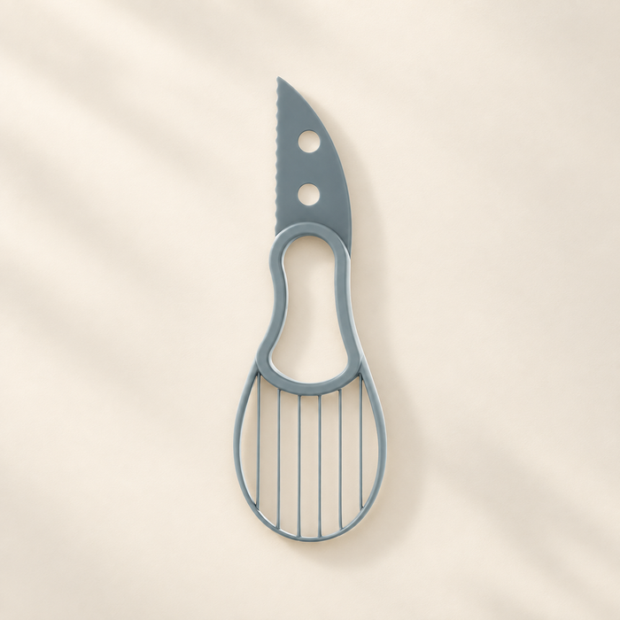Grey-blue avocado slicing tool with serrated edge and oval grid on an ivory surface.