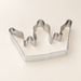 Stainless steel crown-shaped cookie cutter on an ivory surface.