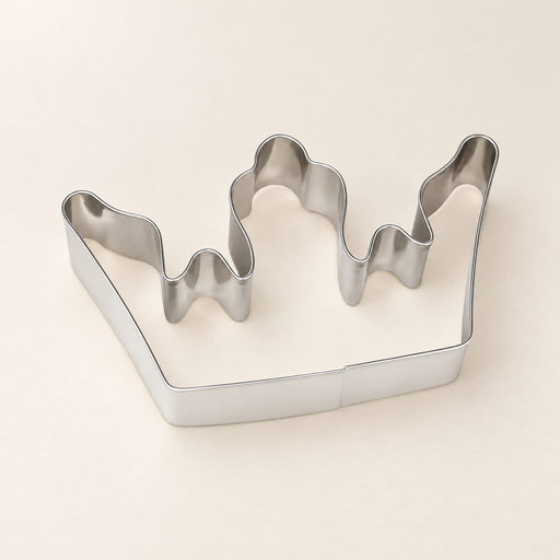 Stainless steel crown-shaped cookie cutter on an ivory surface.