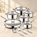 Stainless steel cookware set with six lids and three utensils on an ivory counter.