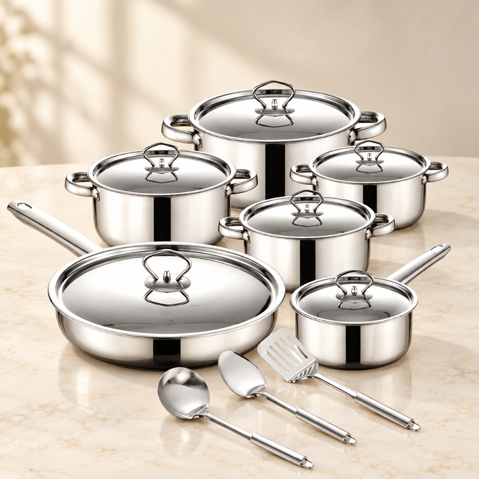 Stainless steel cookware set with six lids and three utensils on an ivory counter.