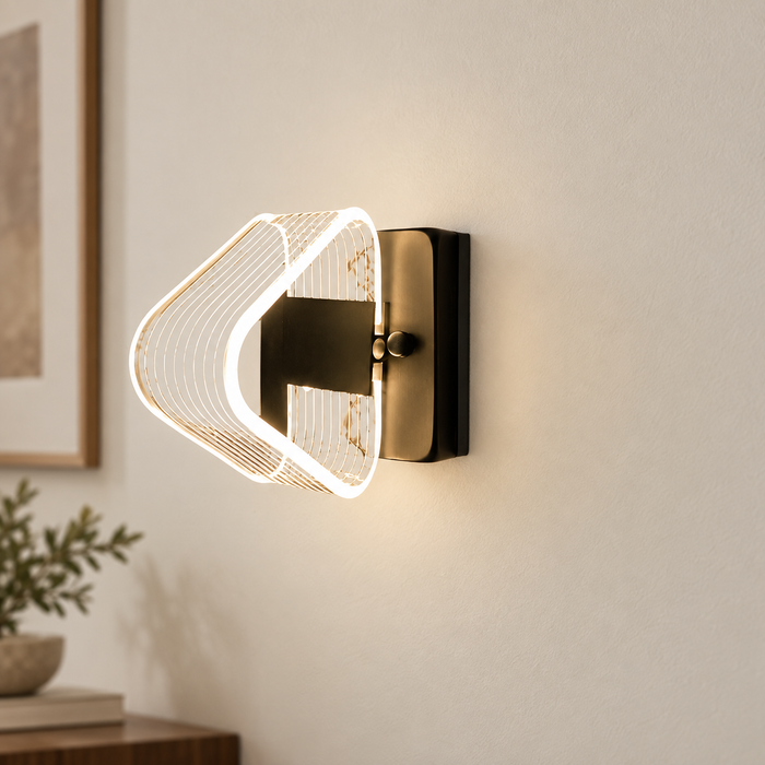 Triangular illuminated wall lamp with a gold-toned mount on a warm neutral wall.
