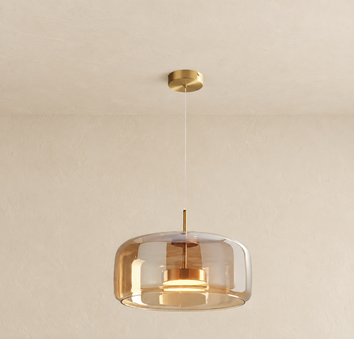 Amber glass pendant light with a gold canopy and stem, suspended against an ivory interior.