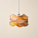 Wooden ribbon pendant light glowing warmly against an ivory wall.