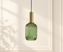 Green ribbed glass pendant light with a gold cylindrical holder against an ivory wall.