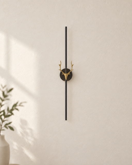 Black vertical wall light with a gold deer motif on an ivory wall.