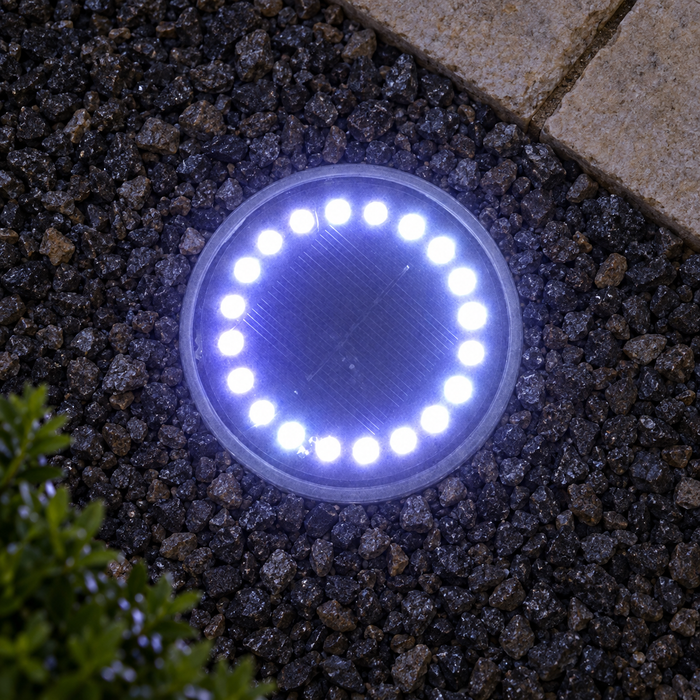 Round solar ground light installed beside a stone path