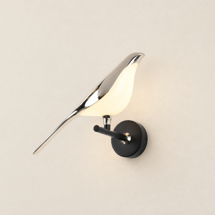 Silver bird wall lamp mounted on ivory plaster wall