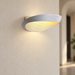 White oval wall lamp illuminating an ivory wall.