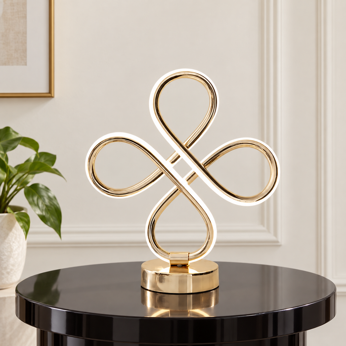 Gold-tone four-loop table lamp on a black side table.