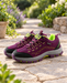 Plum and lime hiking shoes with black toe caps and grey midsoles on a stone garden path.