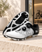 White and black patterned cycling shoes with dial closures, showing the upper and sole on a pale stone ledge.