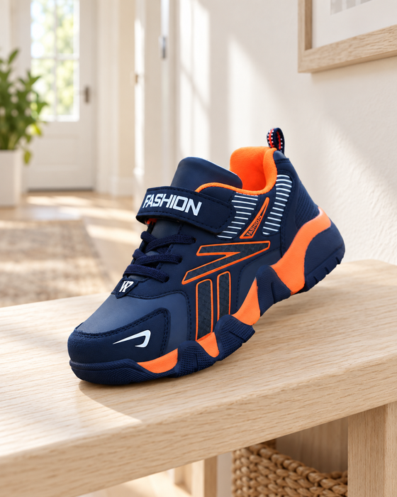 Navy and orange children's sneaker with a fastening strap on a pale wooden bench.
