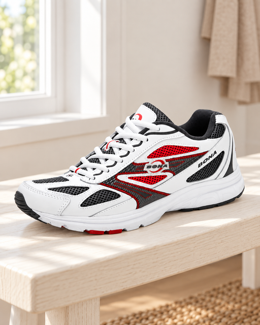 White, black and red mesh sneaker on a pale wooden bench beside a window.