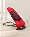 Red and black mesh rocking chair in an ivory room.
