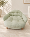 Pale green corduroy pet bed with wooden feet on an ivory stone floor.