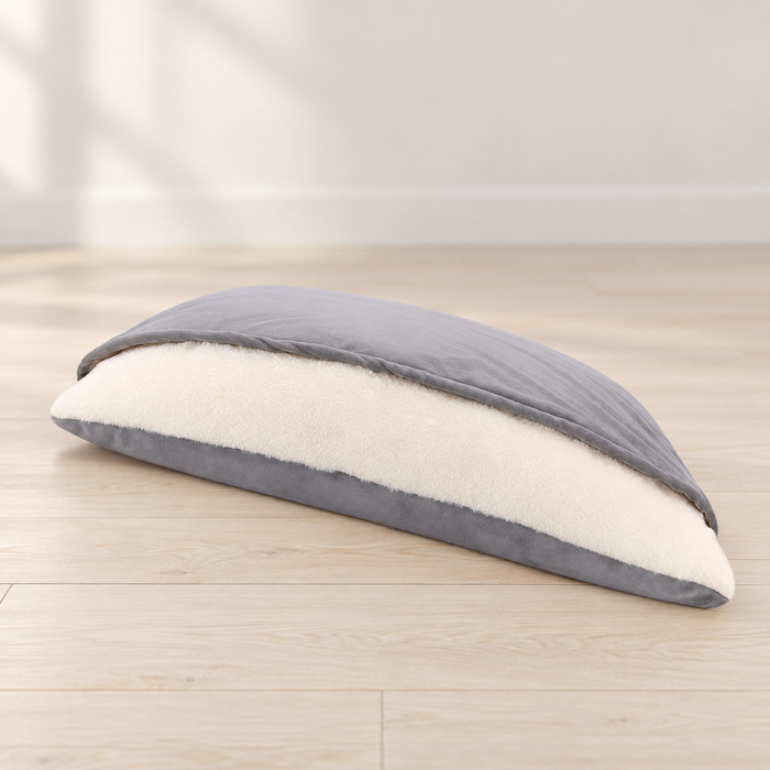 Grey pet sleeping bag with soft ivory lining on a pale wood floor.