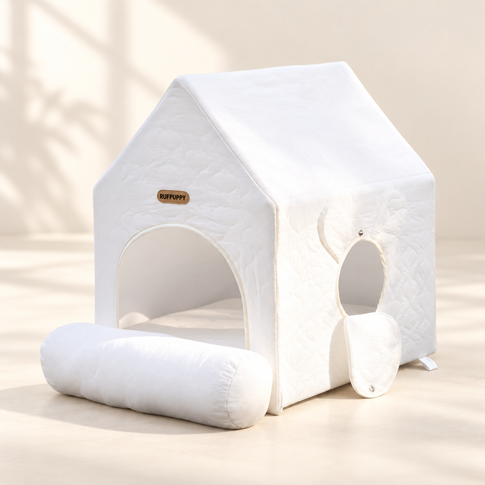 White quilted pet house with rolled entrance flap on ivory floor