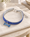 Blue rhinestone pet collar with a bone-shaped pendant, silver-tone clasp and extension chain on ivory linen.
