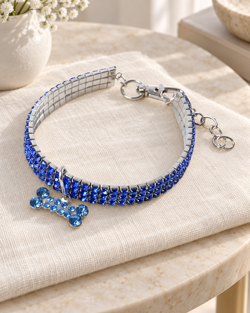 Blue rhinestone pet collar with a bone-shaped pendant, silver-tone clasp and extension chain on ivory linen.