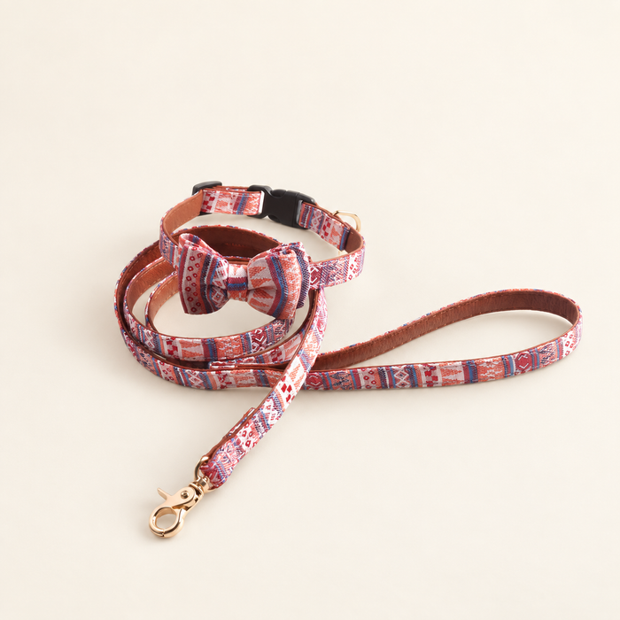 Patterned bow collar and matching leash with a gold-coloured clasp on an ivory surface
