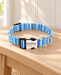 Blue and white patterned dog collar with a silver engraved clasp on a light wooden bench.
