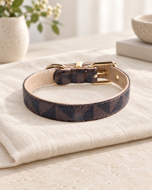 Brown and charcoal patterned pet collar with beige lining and gold-tone hardware on ivory linen.