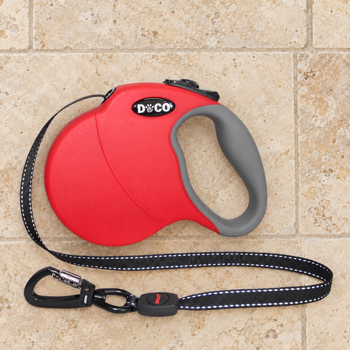 Red and grey retractable dog leash with a reflective black strap and locking clasp on an ivory floor.