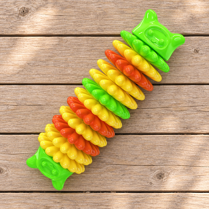 Green, yellow and orange disc-shaped dog toy on a wooden patio surface.