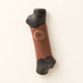 Black and brown branch-shaped dog chew toy on ivory surface